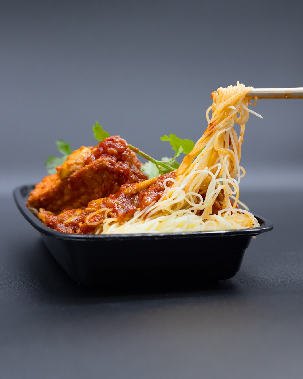 Noodles lifted with chopsticks in a close-up food photograph