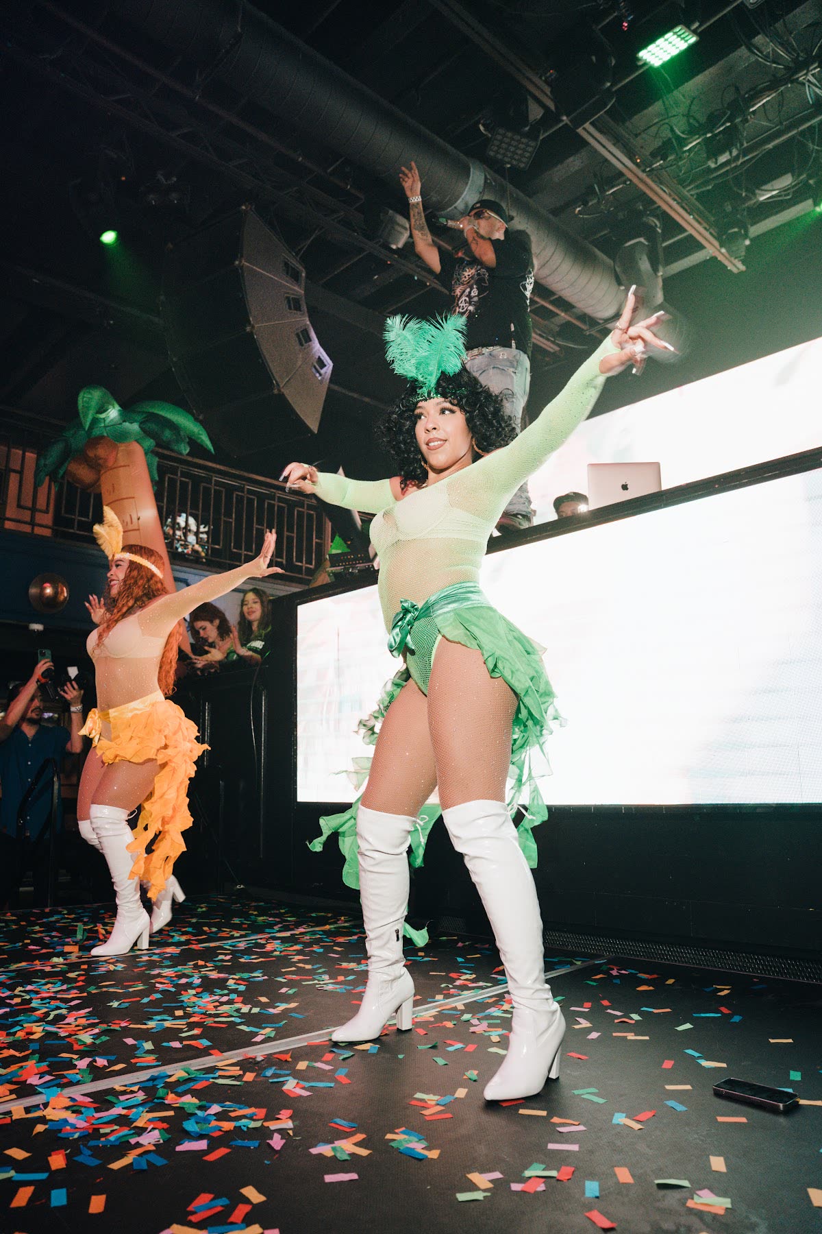 Dancers in green and orange costumes performing at a nightclub