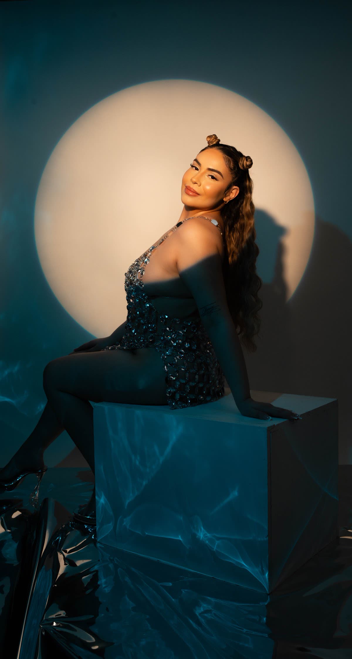 Studio portrait framed by a circular spotlight on a teal set